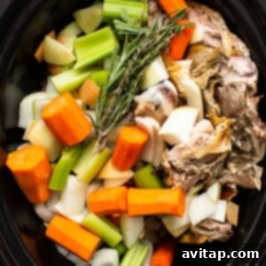 Vegetables and turkey bones arranged in a slow cooker.