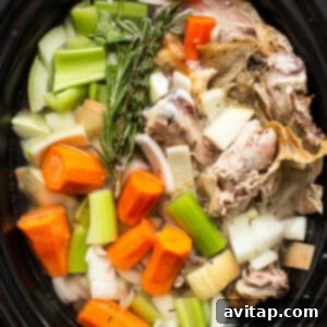 Turkey stock ingredients covered in water within the slow cooker.