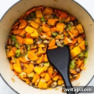 A pot filled with vegetables and turkey wild rice soup, alongside a black spatula.