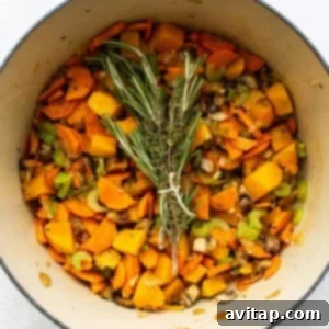 A pot filled with turkey, wild rice soup and sprigs of rosemary.
