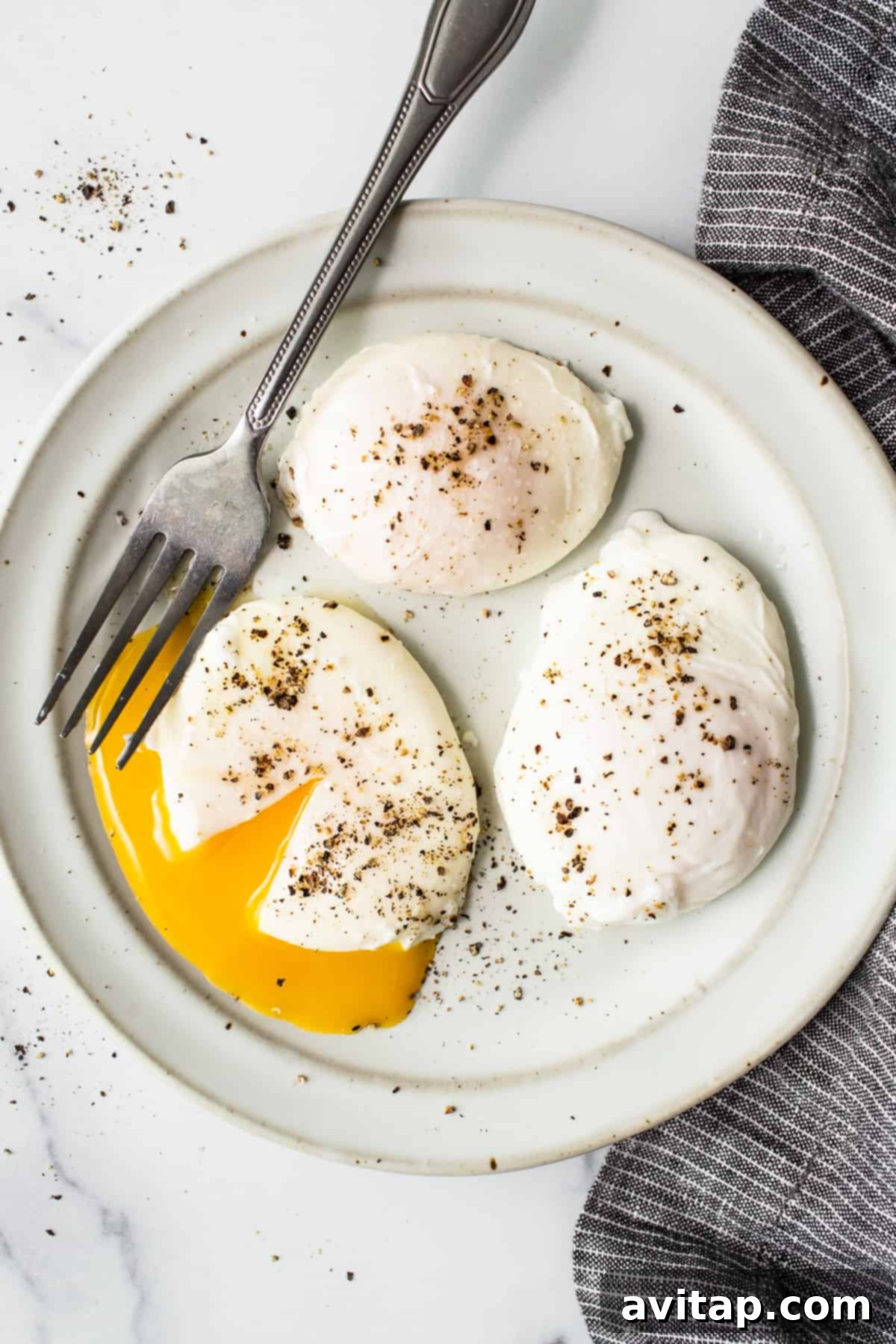Flawless Poached Eggs Every Time 2 Two perfectly poached eggs on a white plate, ready to be served, showcasing firm whites and vibrant yolks.