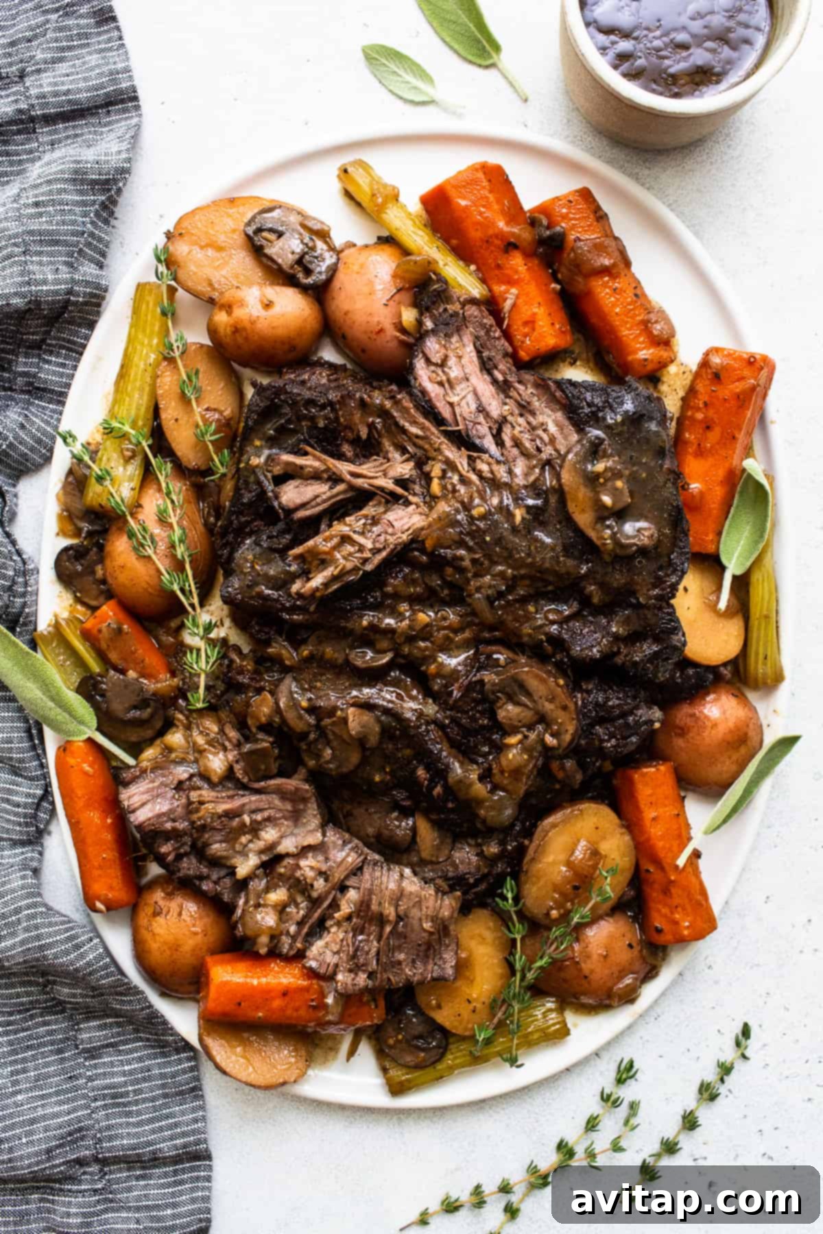 A perfectly cooked pot roast resting on a plate, garnished with fresh herbs, showcasing its tender texture and rich gravy.