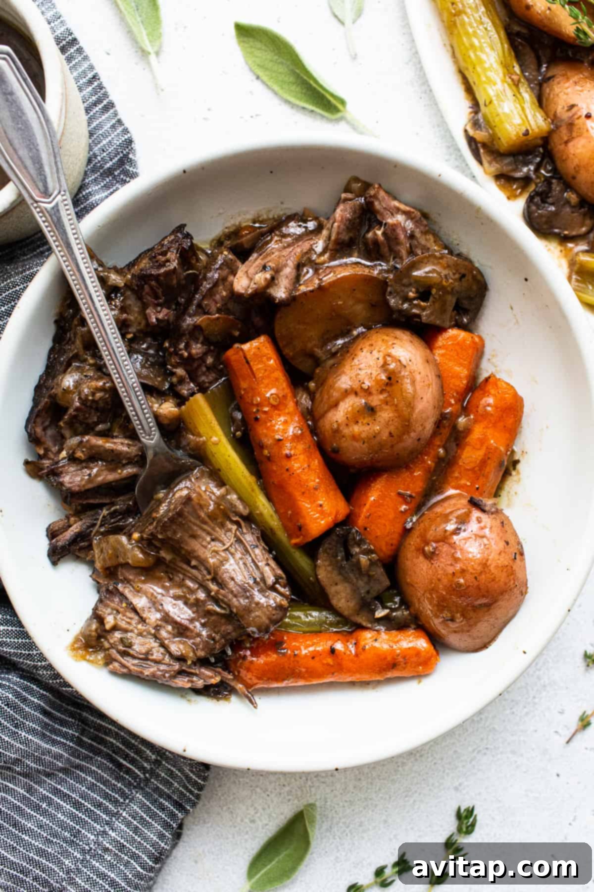A serving of pot roast with tender shredded beef and vegetables in a bowl, with a fork ready to dig in.