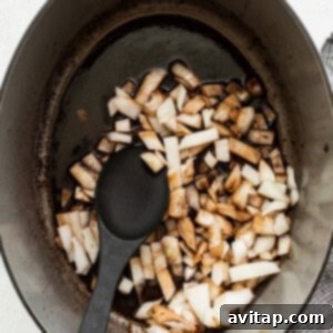 A pot with onions in it and a black spoon.