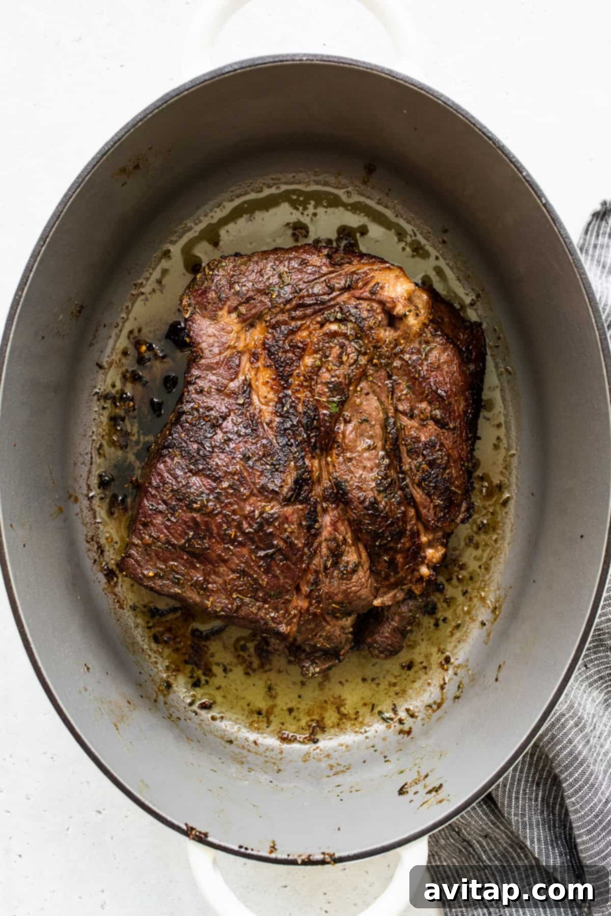 A seared chuck roast sizzling in a Dutch oven, demonstrating a perfect golden-brown crust.
