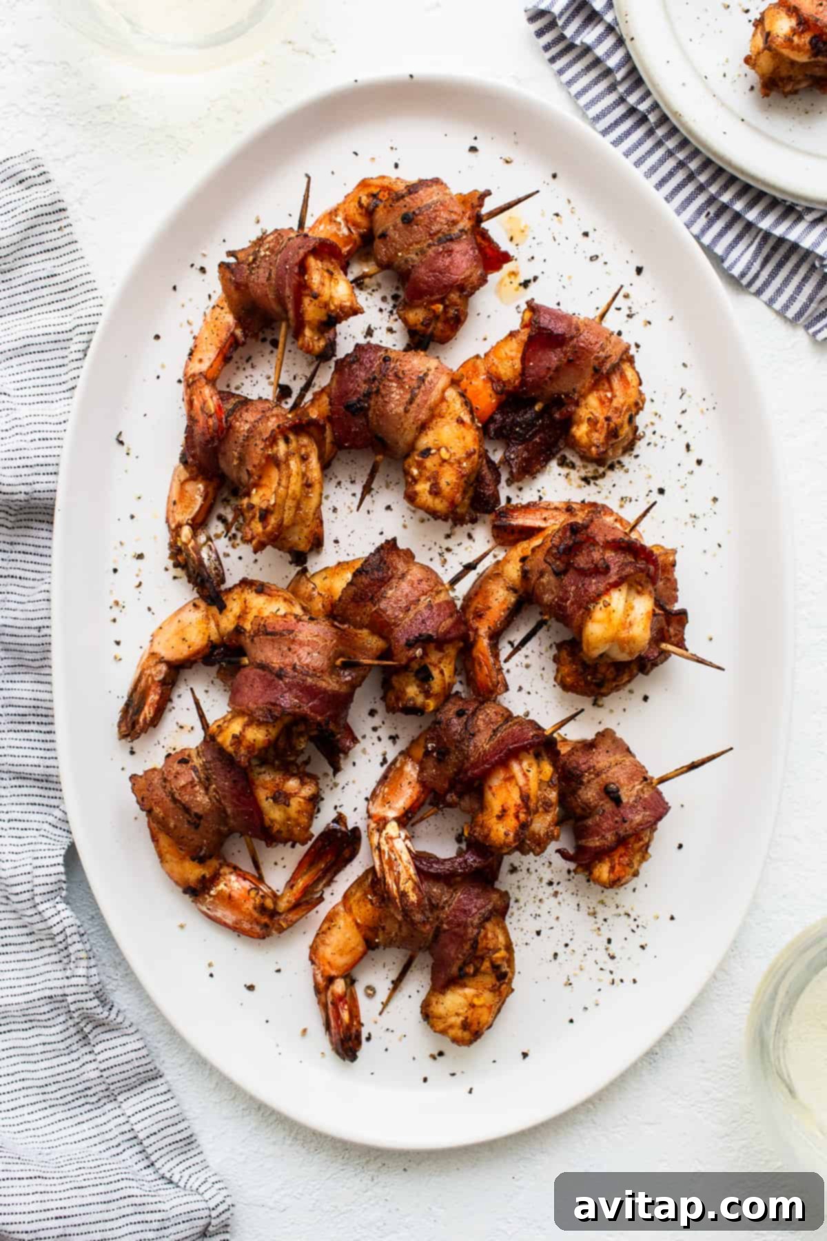 Perfectly cooked bacon wrapped shrimp arranged beautifully on a serving platter, ready to be enjoyed as an appetizer.