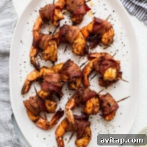 Bacon wrapped shrimp skewers on a white plate.