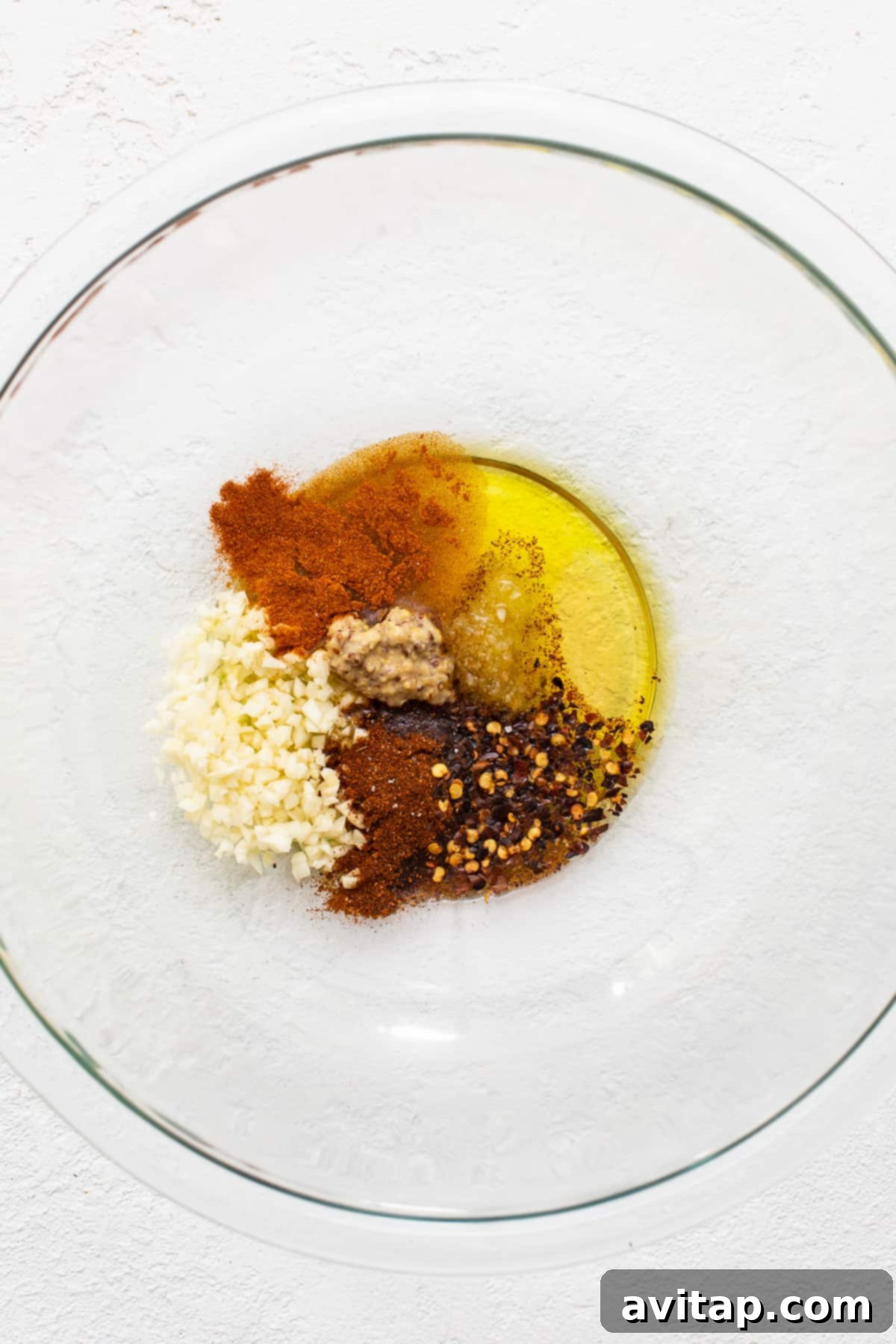 A bowl filled with fresh shrimp marinade ingredients including lemon, garlic, honey, and spices, ready to be mixed.