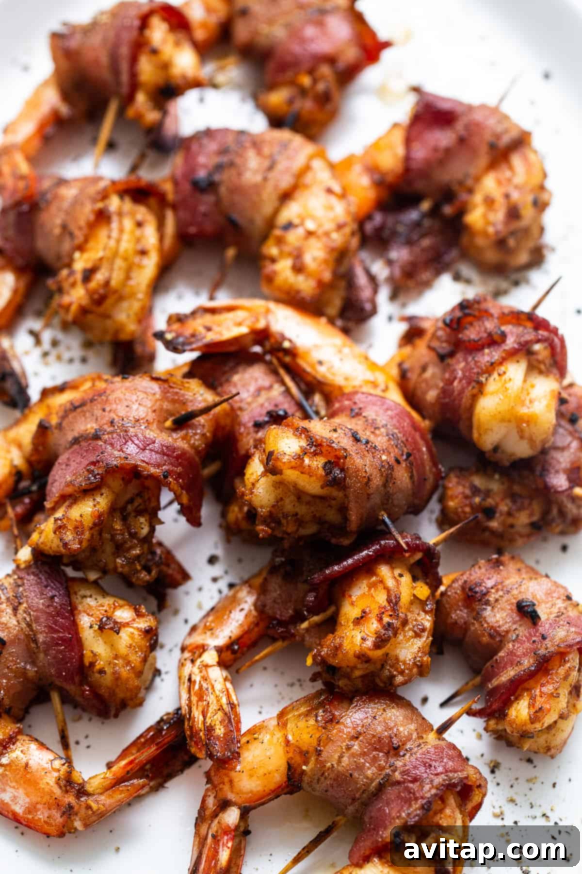A vibrant platter of freshly cooked bacon wrapped shrimp, garnished with fresh herbs, ready for serving at a gathering.