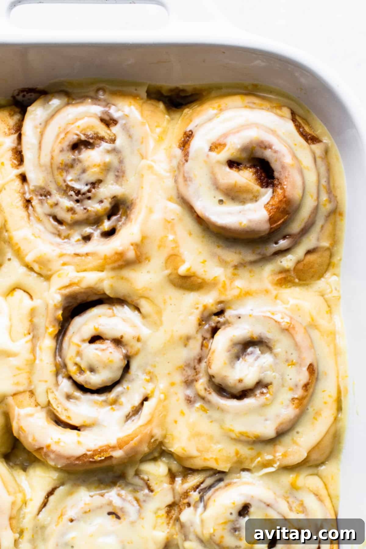 A freshly baked sweet orange roll, golden brown and glazed, sitting in a pan, ready to be served.