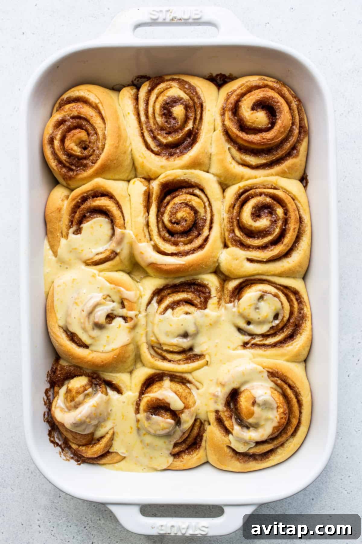 A sweet orange roll generously covered with bright orange frosting, garnished with a sprinkle of orange zest, ready to be enjoyed.