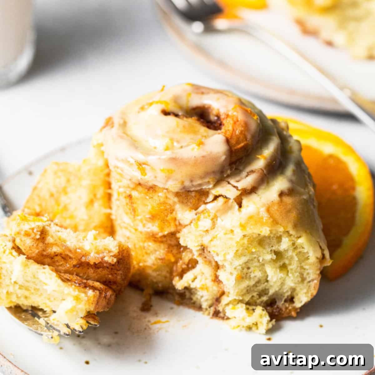 An orange roll with a delightful bite taken out of it, revealing its incredibly gooey, flavorful center and rich layers.