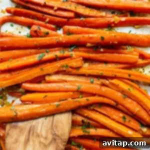 Carrots on a baking sheet with a wooden spoon, garnished with fresh parsley.