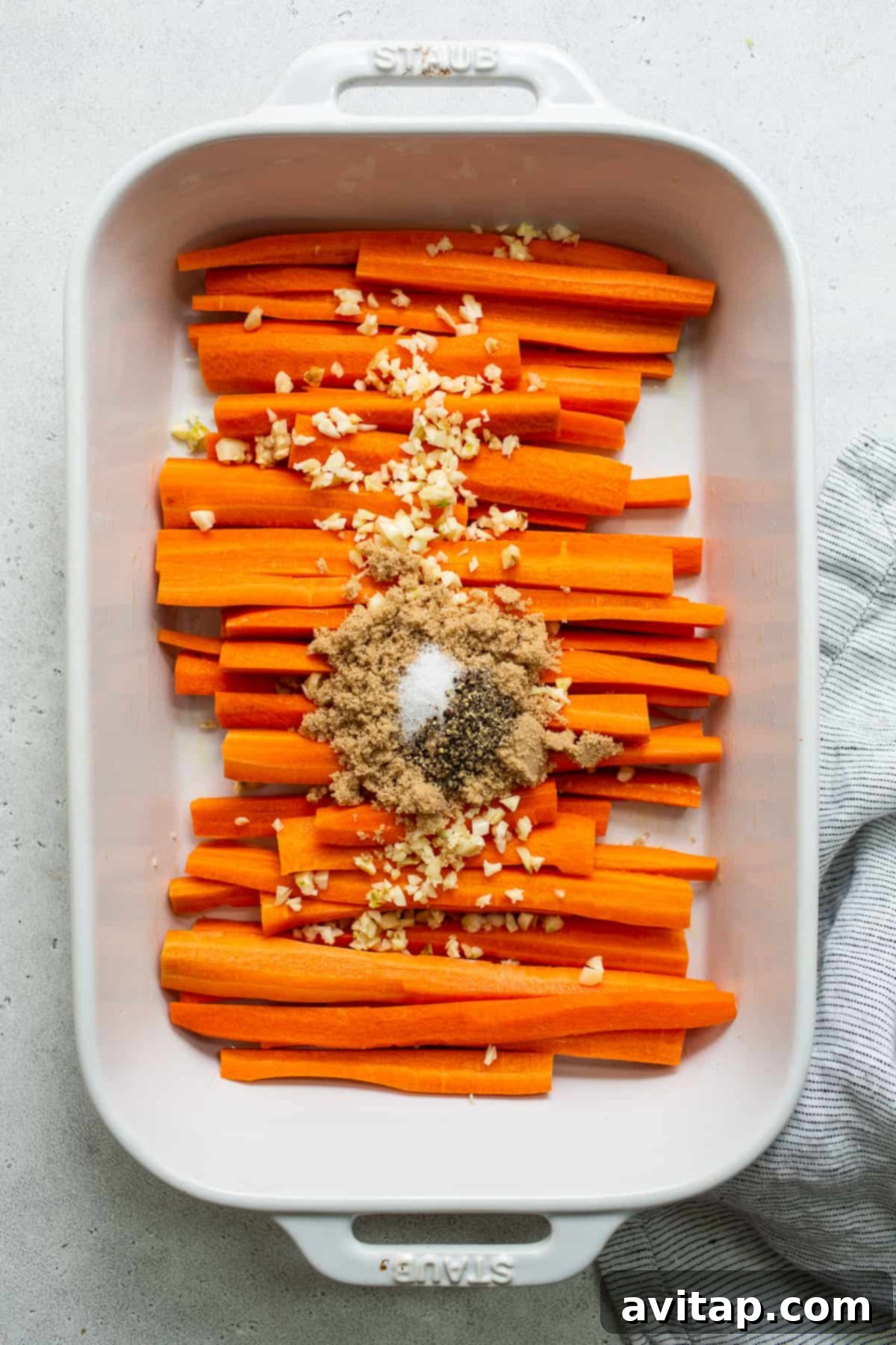 Garlic glazed carrots baking in a casserole dish, glistening with butter and glaze, midway through roasting.