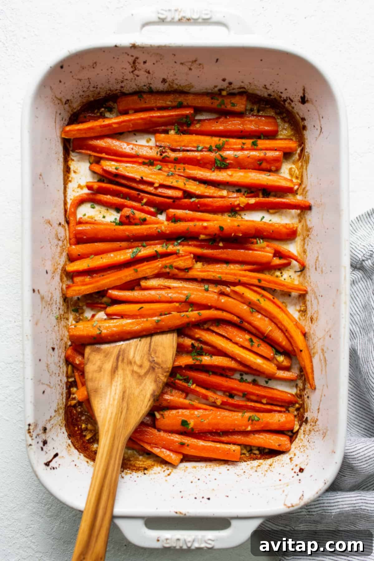 Freshly roasted garlic glazed carrots in a casserole dish, garnished with parsley, ready to be served.