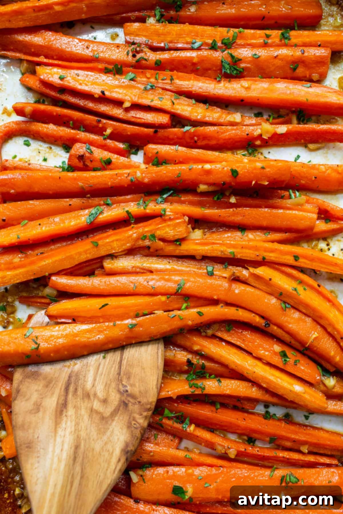 Close-up of garlic glazed carrots on a plate, garnished generously with fresh parsley.