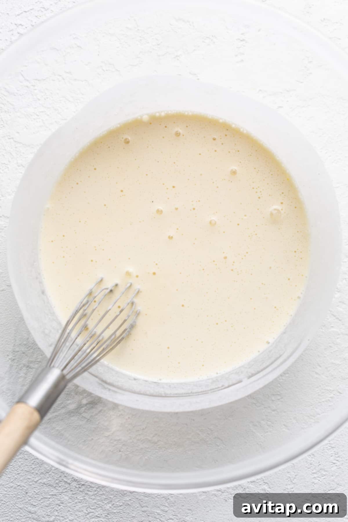 Smooth, melted eggnog ice cream in a mixing bowl, forming the luxurious base for the creme brulee.
