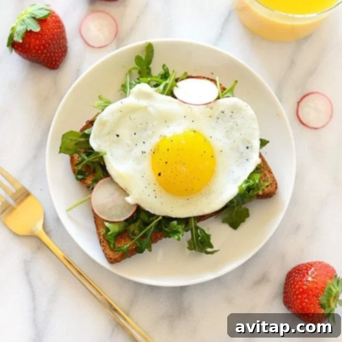 15 Delicious Breakfast Egg Recipes 16 A gourmet toast topped with a fried egg, creamy avocado, fresh arugula, and radishes, perfect for breakfast or brunch.