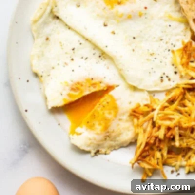 A delicious breakfast plate featuring two perfectly cooked over-medium eggs with crispy edges, alongside roasted potatoes and toast.
