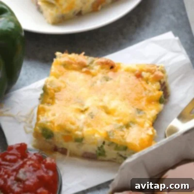 A generous slice of Denver omelet breakfast casserole, rich with peppers, ham, and cheese, on a plate.