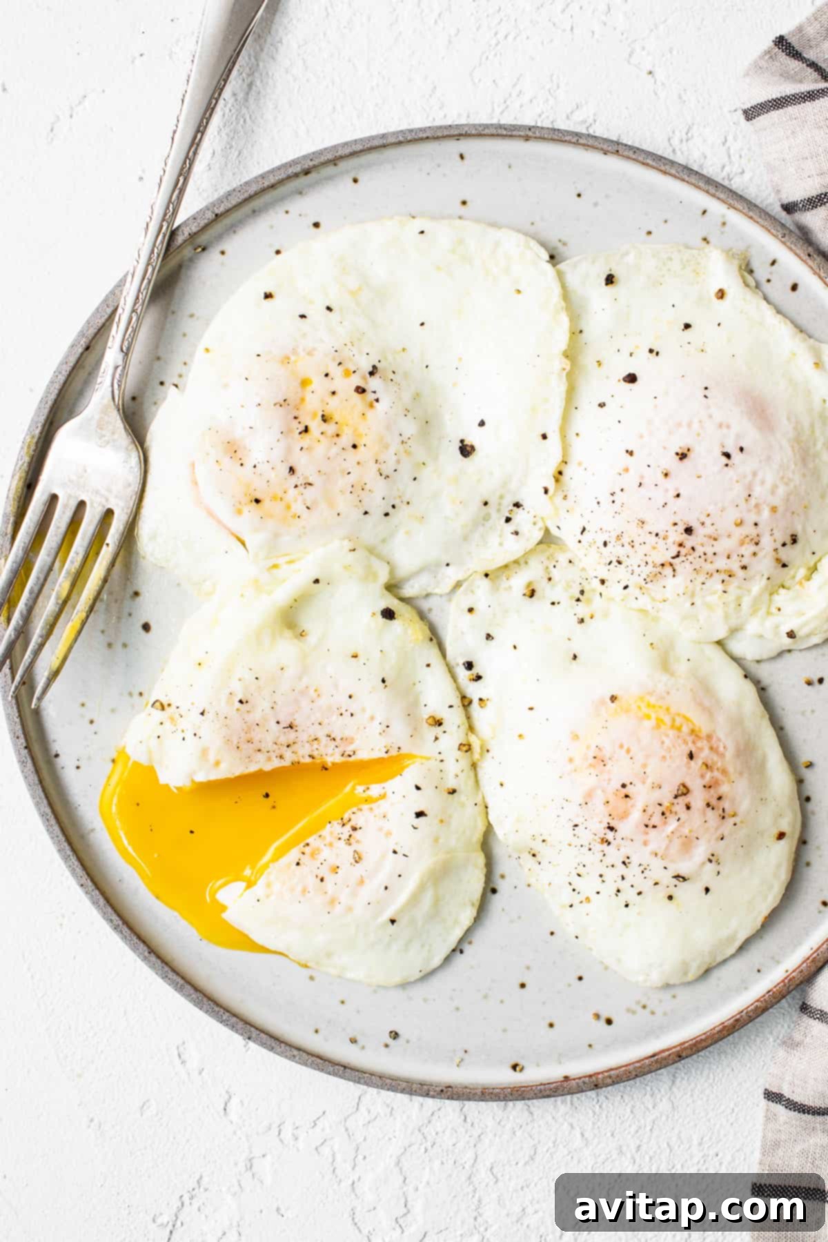 Serve your over easy eggs immediately for the best experience. A stack of over easy eggs on a plate, ready to be served.