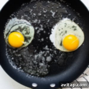 Perfectly Poached Eggs 4 Two fried eggs cooking in a frying pan.