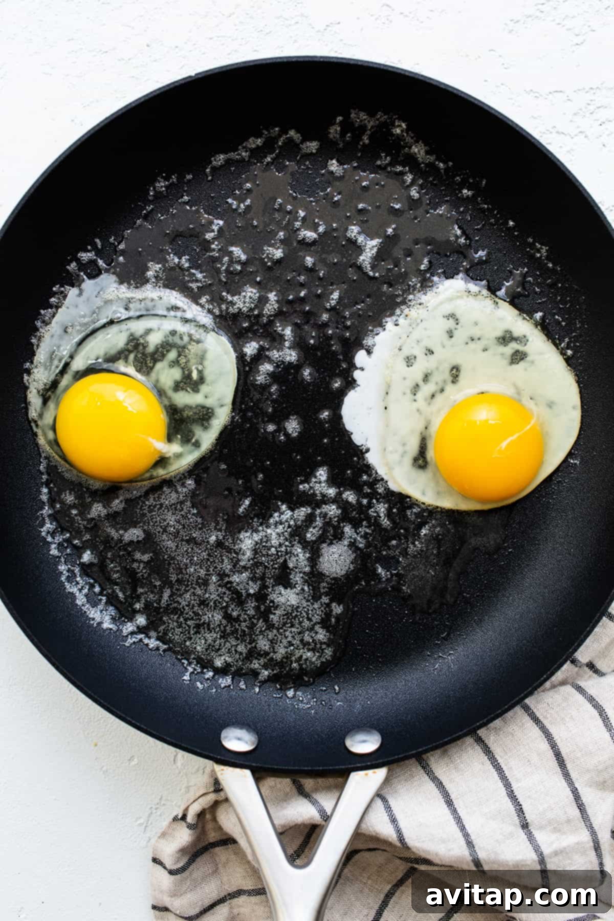 Observe the eggs as they cook to perfect over easy consistency. Eggs gently cooking in a nonstick skillet.