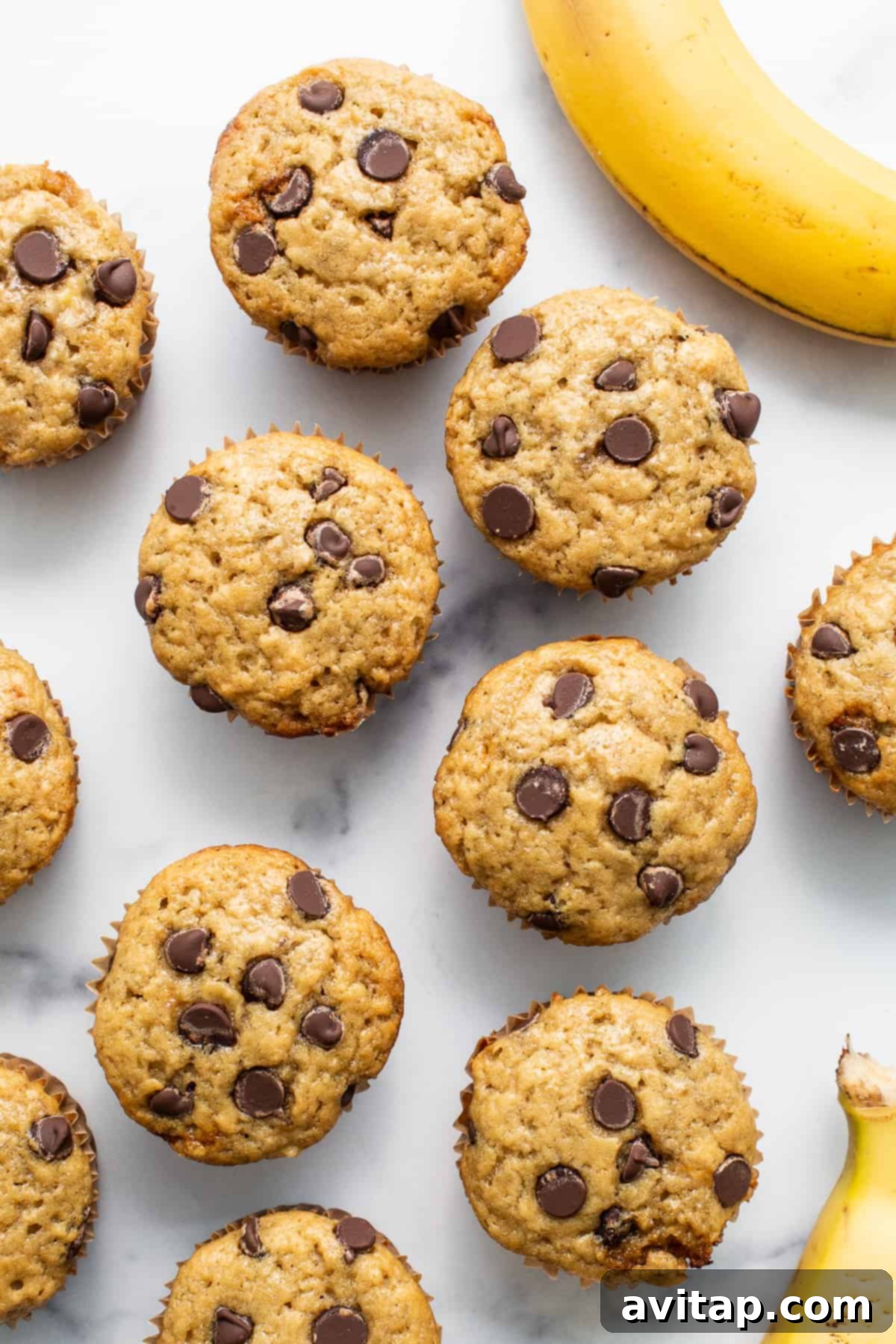Moist, fluffy, and perfectly sweet banana bread muffins. Freshly baked banana bread muffins arranged on a rustic wooden table, ready to be enjoyed. They are golden brown and perfectly domed.
