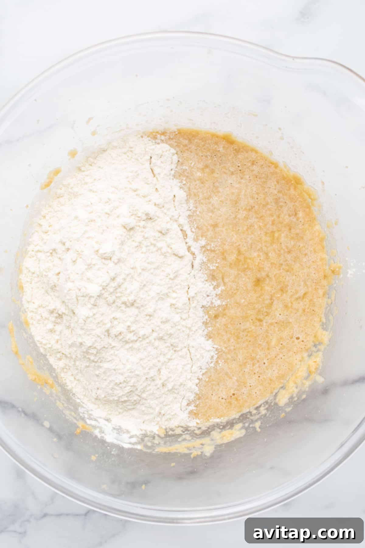 Muffin batter in a bowl, ready for the next step. Smooth, golden banana bread muffin batter ready for baking, in a large mixing bowl.