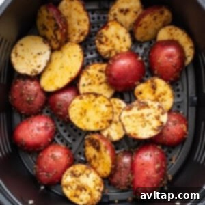 Ultimate Crispy Air Fryer Potatoes 3 Roasted potatoes in an air fryer, showing the seasoning process.