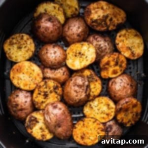 Ultimate Crispy Air Fryer Potatoes 4 Roasted potatoes in an air fryer basket, halfway through cooking.