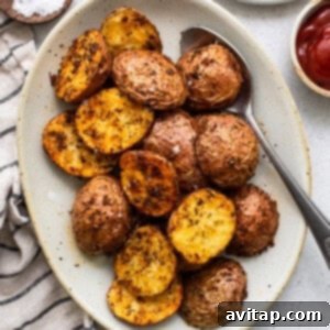 Ultimate Crispy Air Fryer Potatoes 5 Roasted potatoes on a plate with ketchup and a sprinkle of salt.