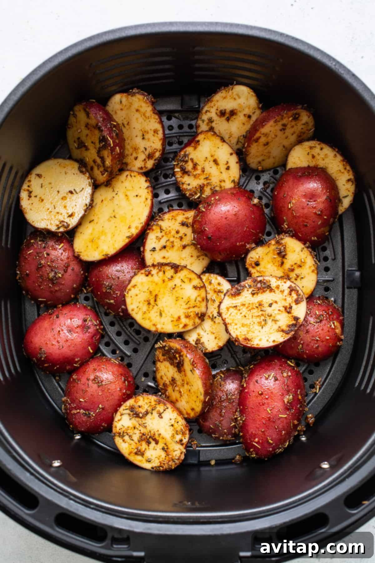 Potatoes Prepped for Air Frying Uniformly sliced and seasoned potatoes arranged in an air fryer basket, ready for cooking.