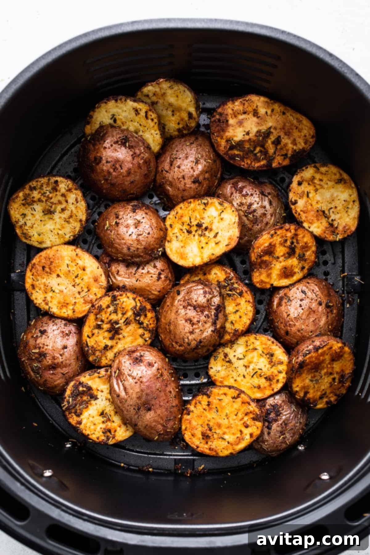 Golden Potatoes in the Air Fryer Perfectly air-fried potatoes glowing golden in the air fryer basket, steam gently rising.