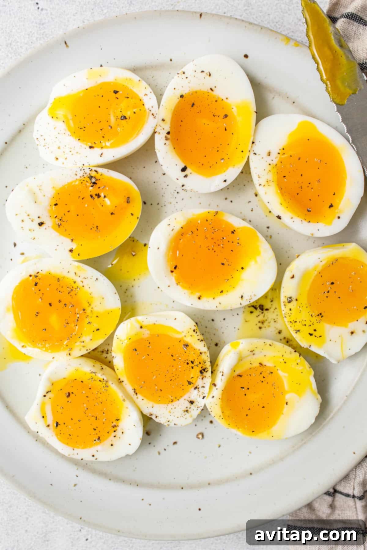 Soft boiled eggs on a plate with salt and pepper, showcasing jammy yolks and firm whites.