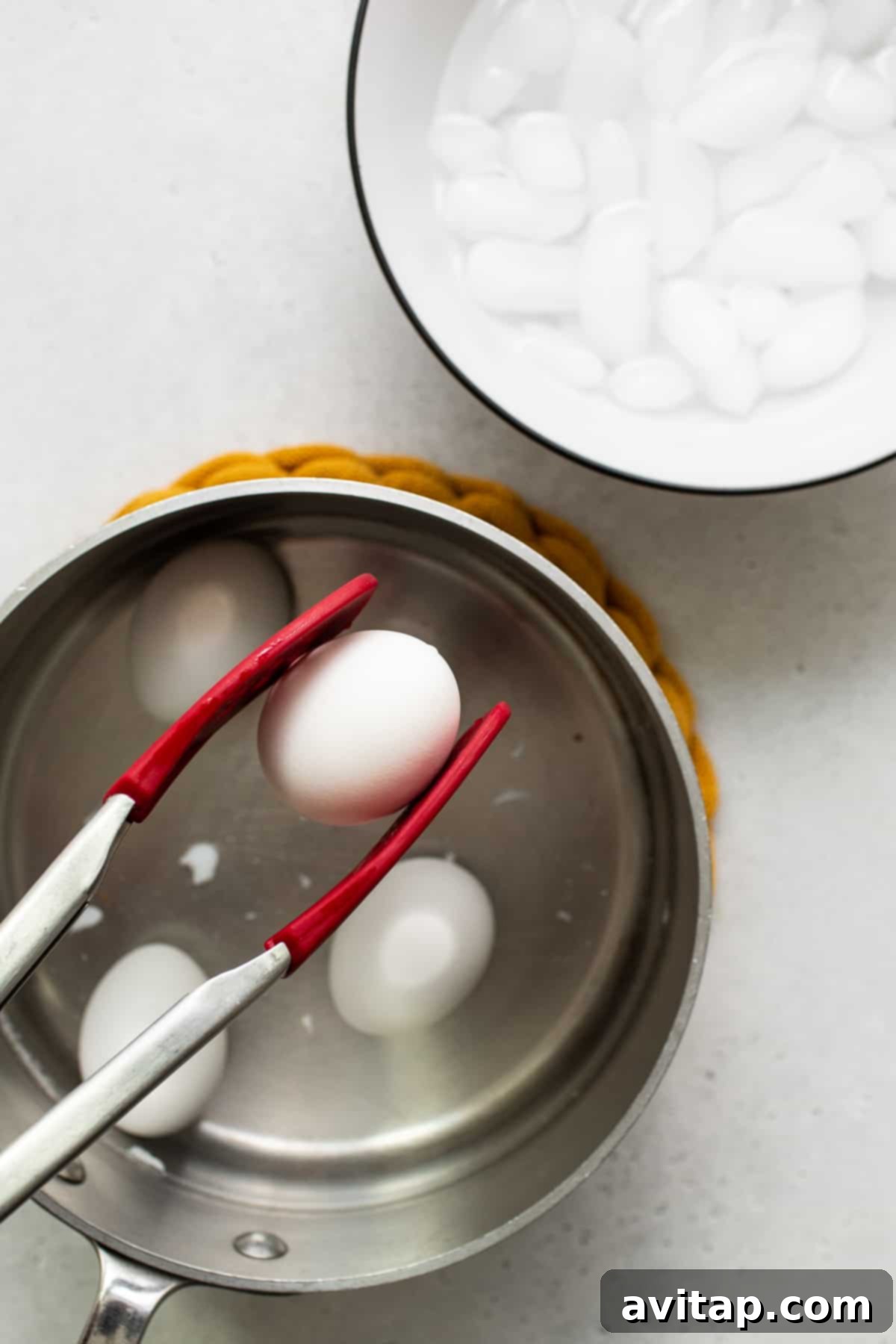 Soft boiled egg being gently held with a set of tongs, showcasing its delicate texture and perfect oval shape.
