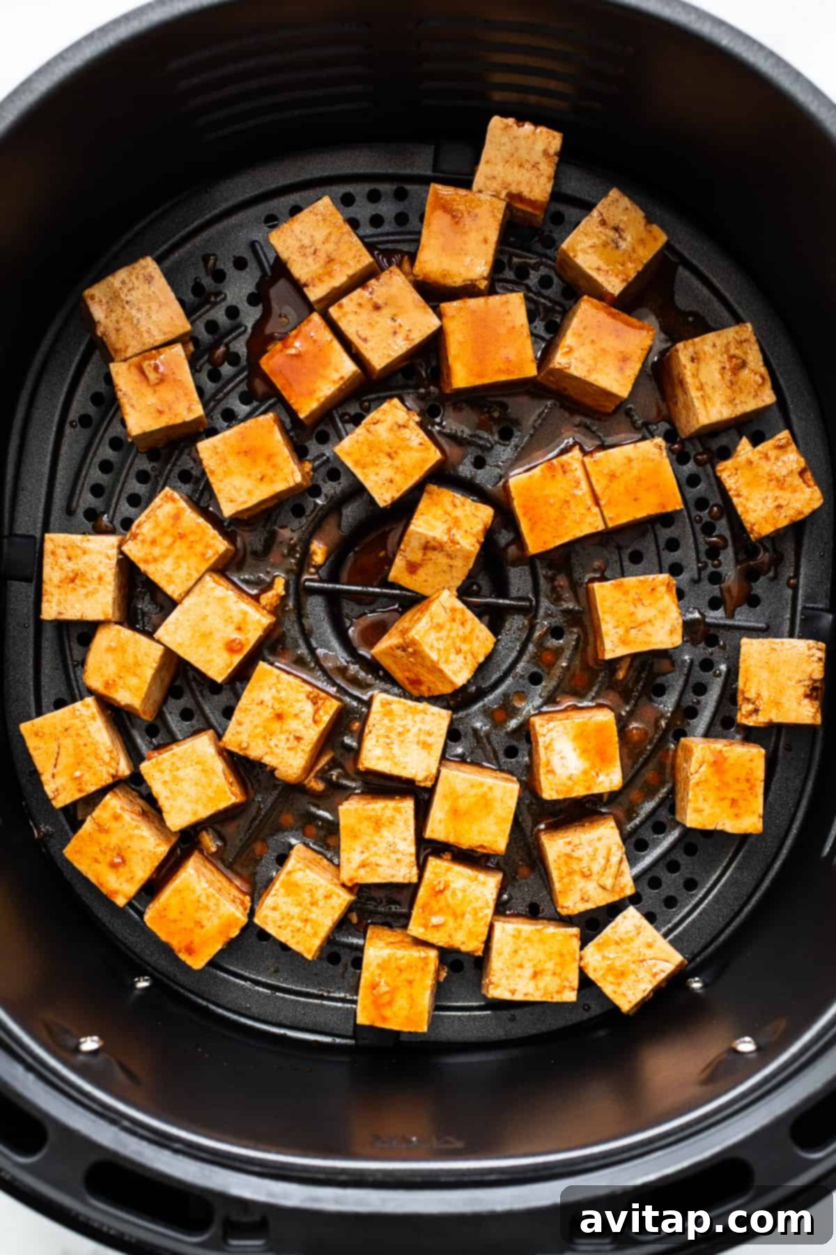 Crispy Air Fryer Tofu 5 Arranging marinated tofu cubes in a single layer inside an air fryer basket, ready for cooking.