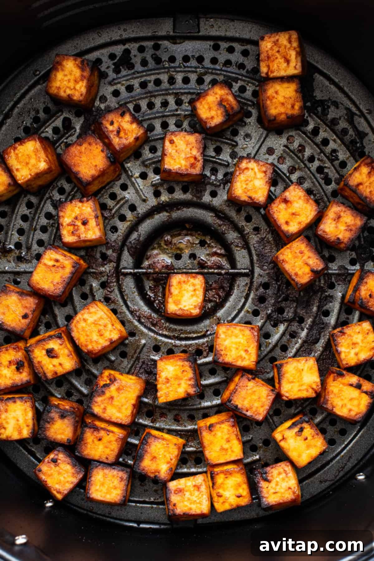 Crispy Air Fryer Tofu 6 Golden brown and perfectly crisped tofu cubes, freshly removed from the air fryer, resting on a plate.