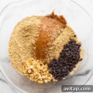 A glass bowl filled with ingredients for peanut butter granola.
