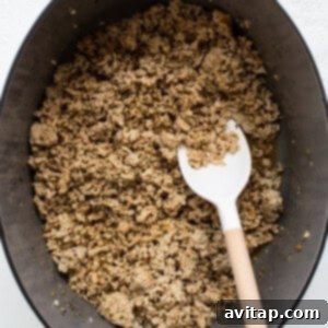 Ground chicken browning in a Dutch oven with a wooden spoon, releasing its flavors.