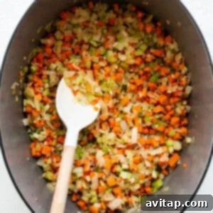 A pot with carrots, onions, and celery sautéing, creating a fragrant base for the bolognese.