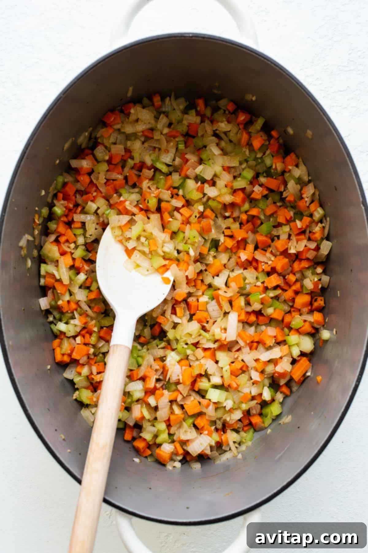 A large stock pot filled with finely minced white onions, carrots, and celery, forming the aromatic base for the bolognese sauce.