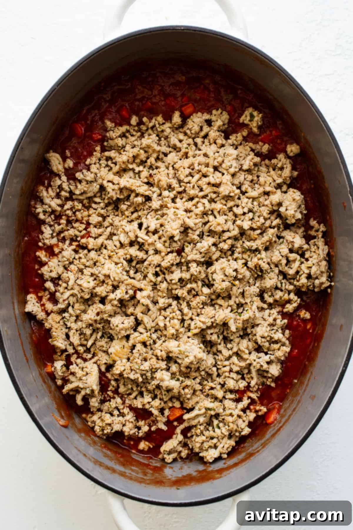 Rich ground chicken bolognese simmering in a large stock pot, showcasing its deep red color and chunky texture, ready to be served over pasta.