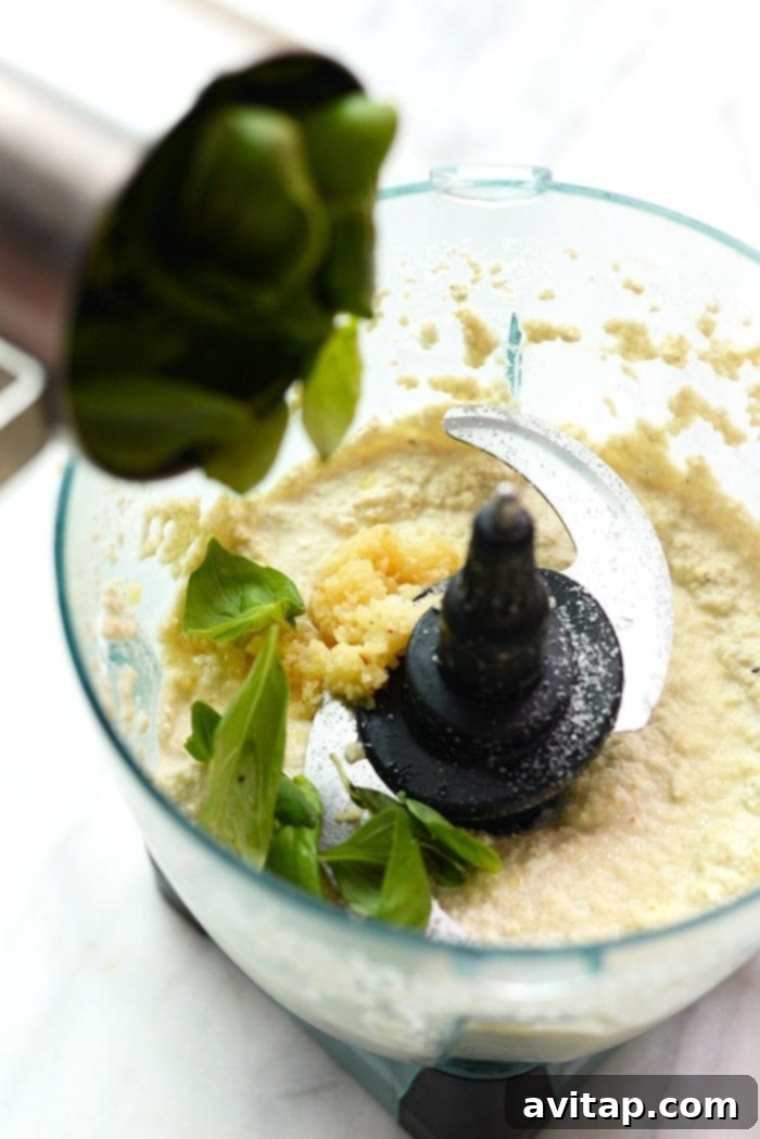 A generous serving of creamy vegan cashew pasta, garnished with fresh basil leaves and red pepper flakes, ready to be served.