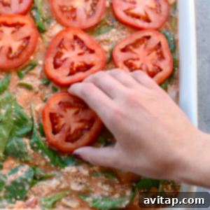a person is removing tomatoes from a Naked Spinach Quinoa Lasagna Casserole.