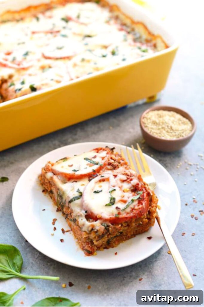 A perfectly portioned slice of spinach quinoa lasagna casserole on a plate with a fork, ready to be enjoyed.