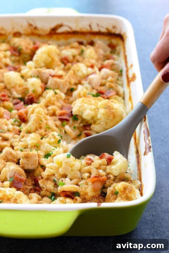Creamy Cauliflower Chicken Mac and Cheese 4 A spoonful of creamy cauliflower chicken mac and cheese being served from a casserole dish.