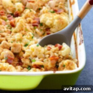 Creamy Cauliflower Chicken Mac and Cheese 6 Cauliflower casserole with chicken and cheese in a green dish with a spoon.