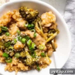 Finished orange chicken casserole in a bowl, topped with sesame seeds and green onions.