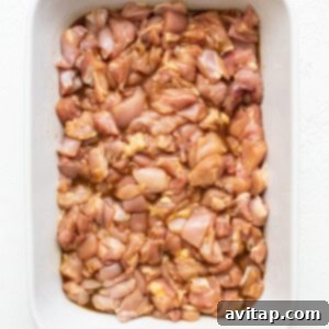 Chicken marinating in orange sauce in a casserole dish.